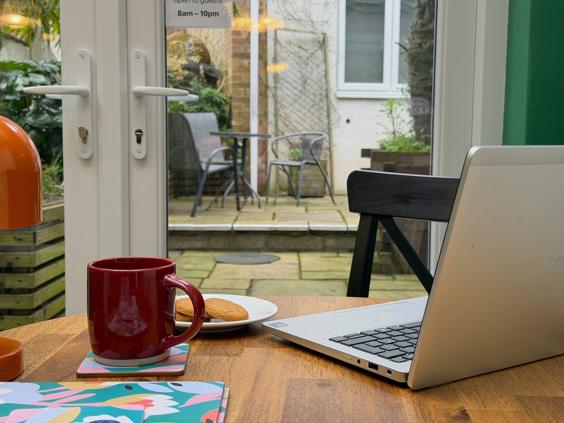 Laptop on the table in the conservatory with the shared courtyard visible behind.