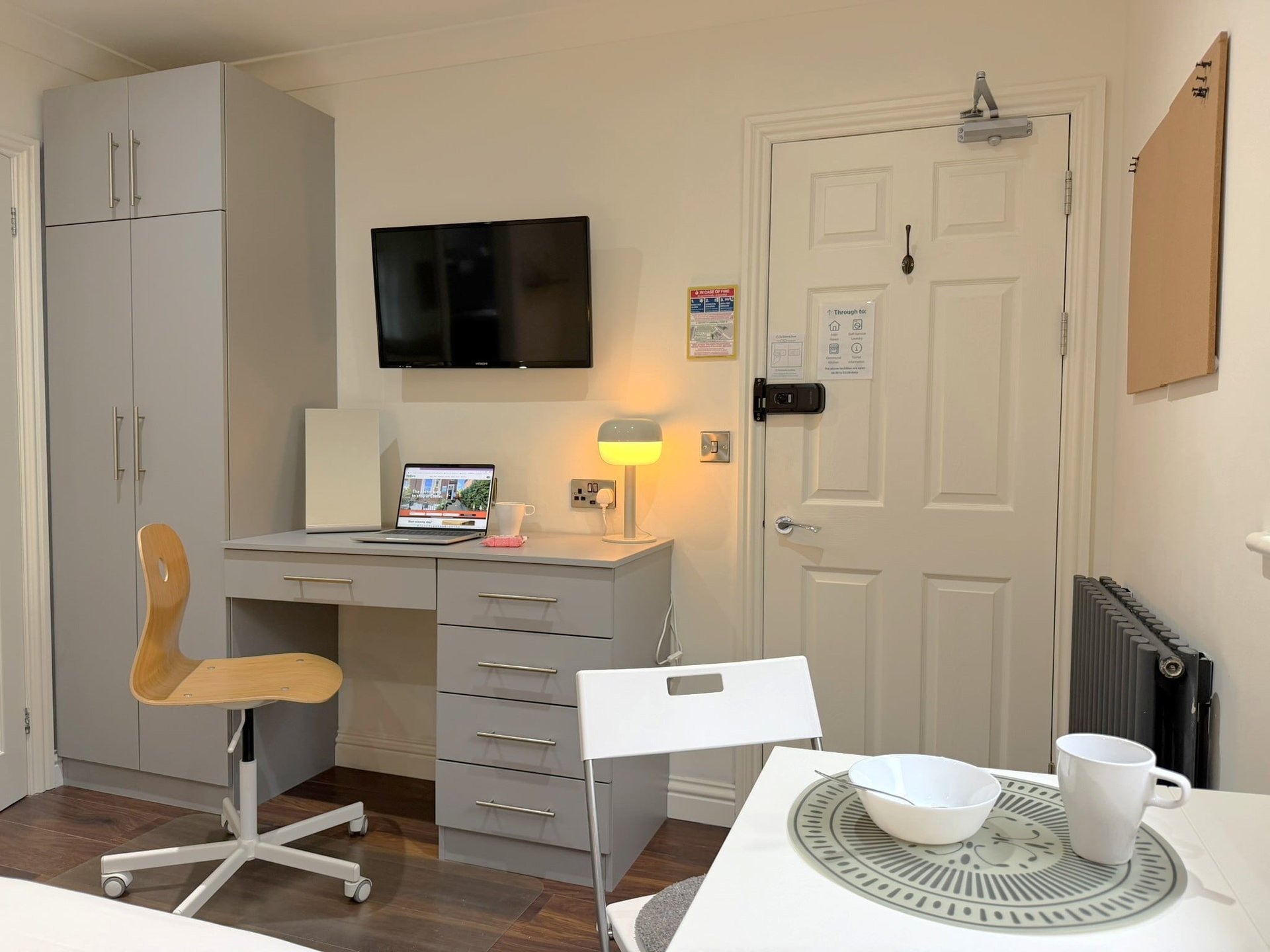 Layout of Studio 10, showing dining table and desk with wardrobe in the background.